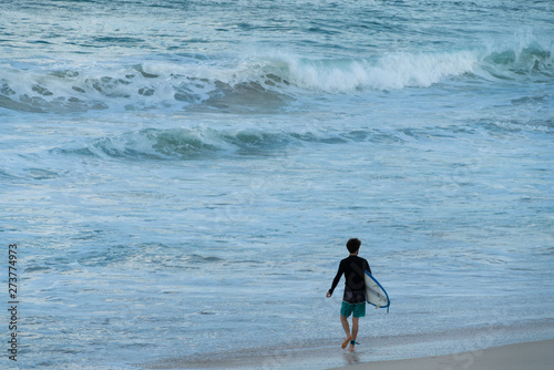 A surfer getting ready for the surf, going surfing in ocean