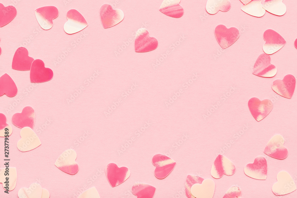 Heart shape confetti on pink pastel holiday background. Festive frame, Valentine's Day. Flat lay, copy space.