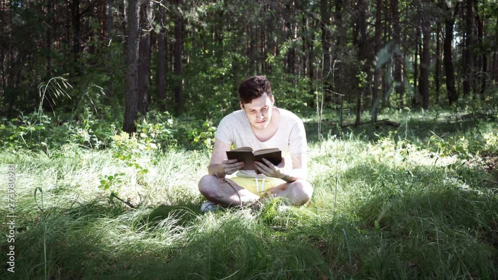 Young handsome man reading book in open space Young handsome man reading book in open space
