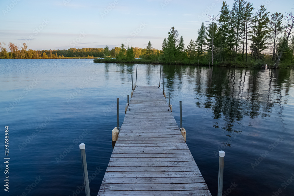 Naklejka premium Pier jutting out into the Chippewa Flowage in front of a wooded island in the Northwoods