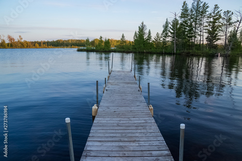 Pier jutting out into the Chippewa Flowage in front of a wooded island in the Northwoods