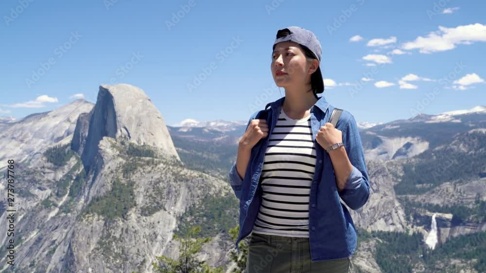 lovely young asian girl in cap with backpack enjoying sunshine on peak of foggy mountain in yosemite national park. female tourist traveler hiker looking sunlight in trip half dome trail usa. lovely young asian girl in cap with backpack enjoying sunshine on peak of foggy mountain in yosemite national park. female tourist traveler hiker looking sunlight in trip half dome trail usa.