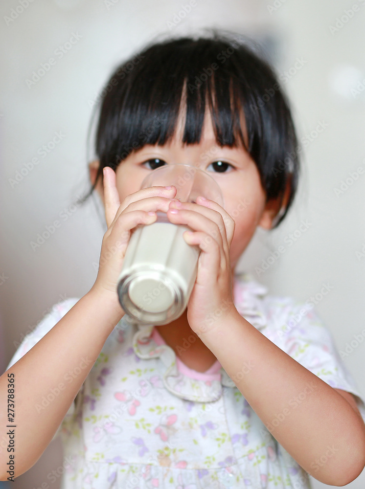 Close up of little girl drinking milk from glass indoors, Focus at hands. Close up of little girl drinking milk from glass indoors, Focus at hands.