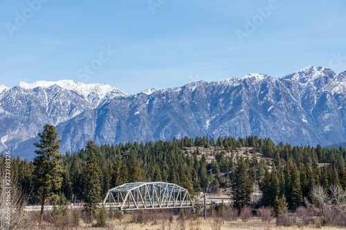 metal bridge over a river with mountain in snow in the background Regional District of East Kootenay Canada.