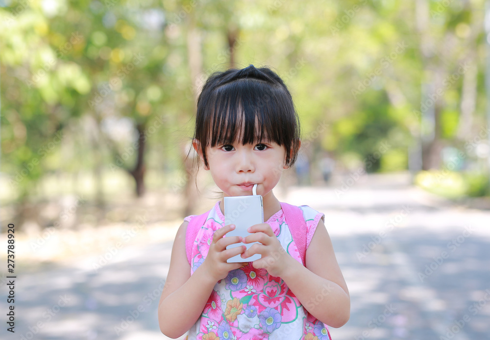 Closeup of little girl drinking milk with straw in the park. Portrait outdoor. Closeup of little girl drinking milk with straw in the park. Portrait outdoor.