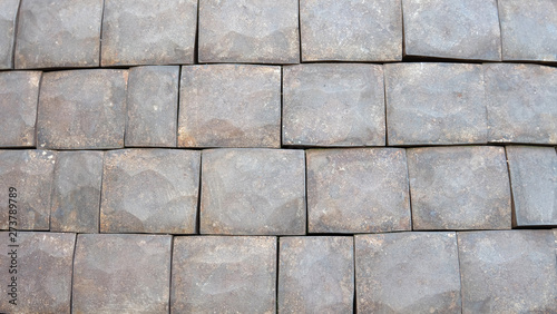 Square stone tiles with uneven surface and shapes arranged side by side into 4 rows.
