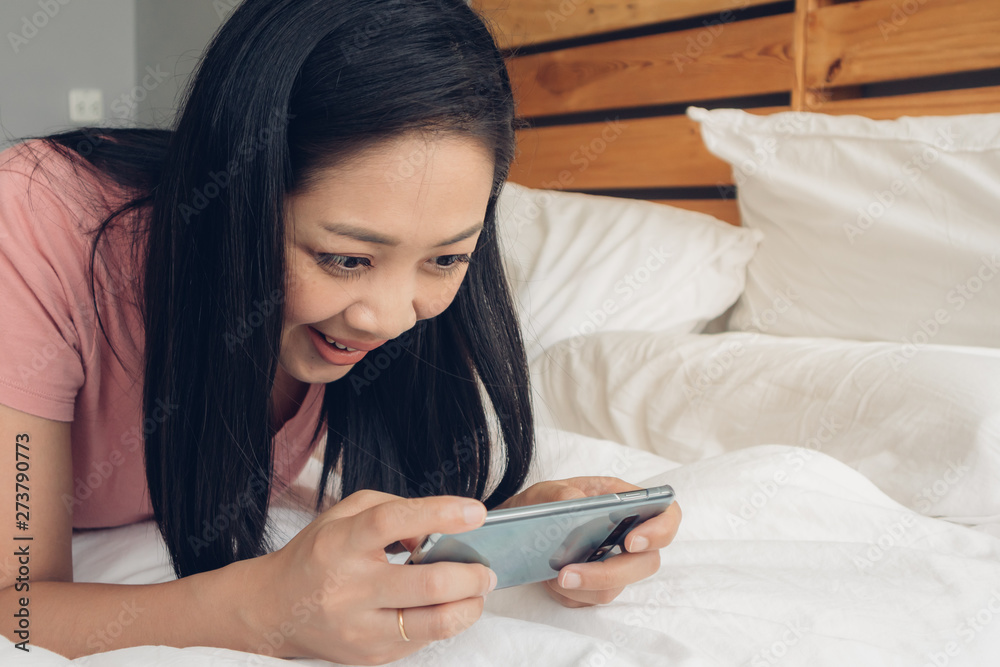 Happy woman is playing mobile game on her bed. Happy woman is playing mobile game on her bed.