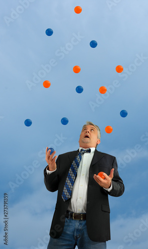 Disheveled out of control man juggling a lot of several balls in the air representing extremely busy domestic life, business stress, overworked, struggling to function, overwhelmed and out of control.