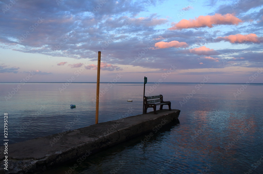 old pier at sunset over water, wooden bench on lake