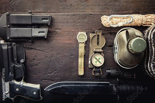 Military tactical equipment for the departure. Assortment of survival hiking gear on wooden background. Top view - vintage film grain filter effect styles photo