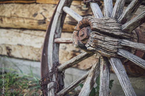 An old wooden wagon wheel with a rusty chain wrapped around it.