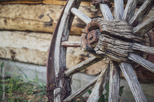 old wooden wagon wheel with a rusty chain wrapping around one of the spokes