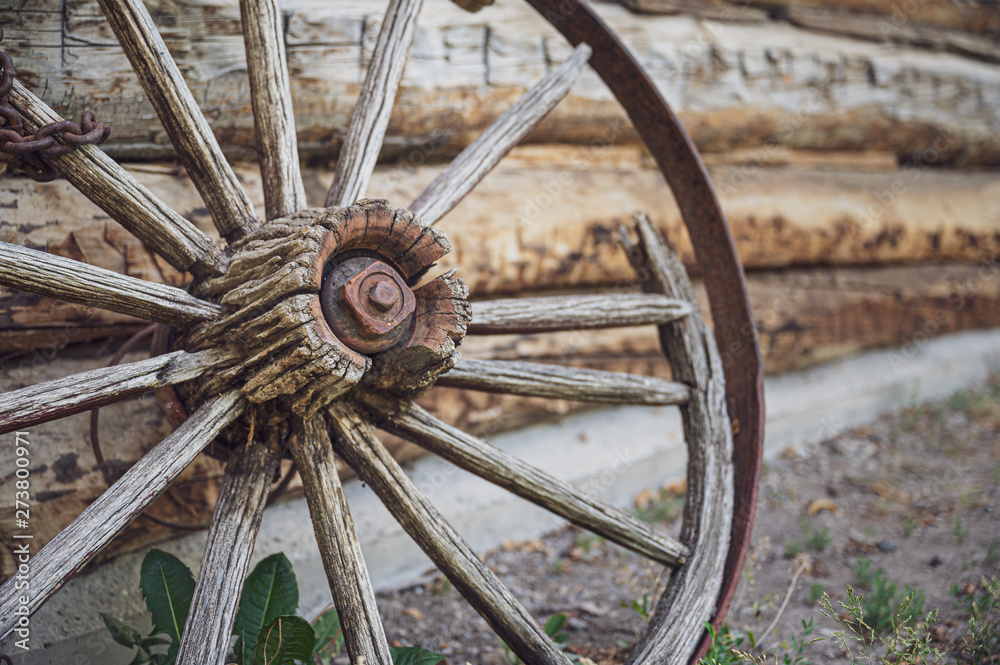 old wooden wagon wheel with a rusty chain wrapping around one of the spokes