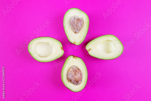 Cut avocado on a pink background. The concept of vegetarianism, healthy eating, organic food rich in vitamins. Minimalism, top view, flat lay. Copy space. Design, summer concept.