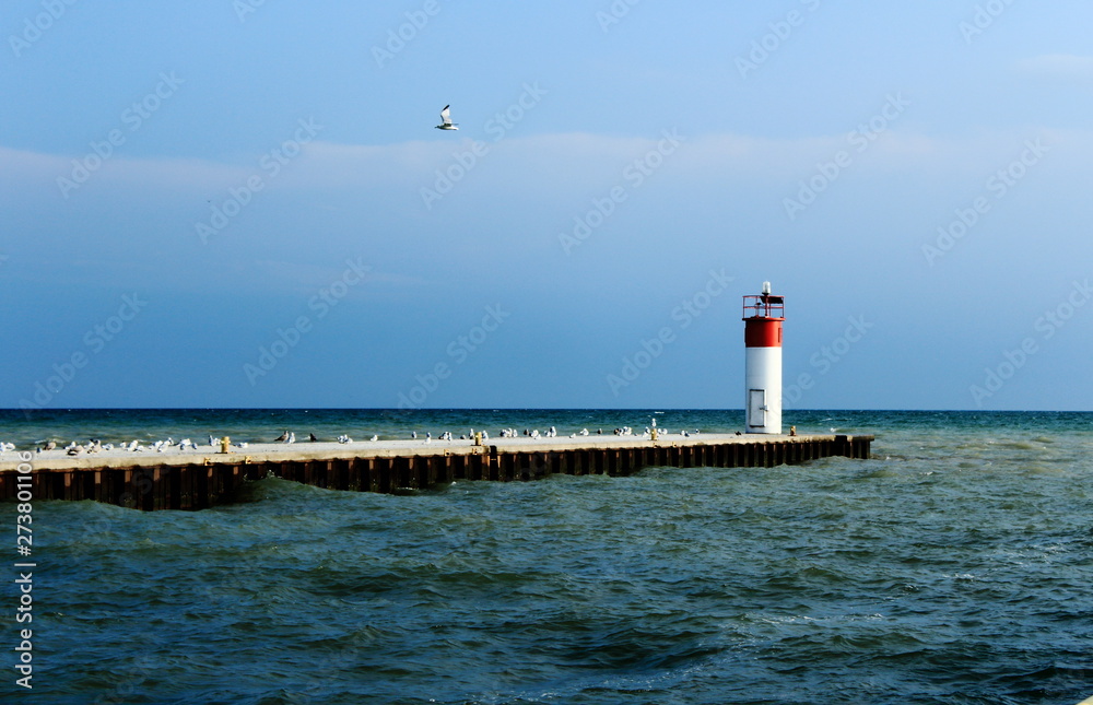 lighthouse and pier at sea, beautiful blue sky with birds