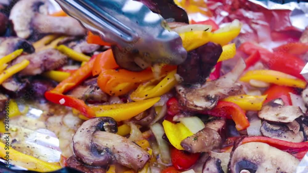 Red and yellow bell peppers being grilled with onions, mushroom and seasonings over hot charcoal Red and yellow bell peppers being grilled with onions, mushroom and seasonings over hot charcoal