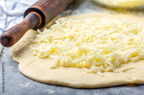 Grated cheese, rolling pin and dough close-up.
