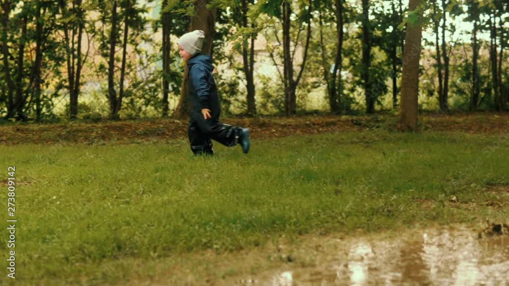 Happy playful baby boy enjoying running on green grass at summer forest park Happy playful baby boy enjoying running on green grass at summer forest park