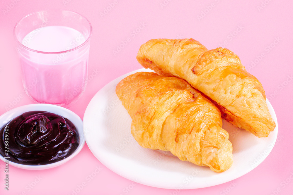Two croissants on white dish and glass of fresh milk on pink back ground with copy space for your text. Breakfast concept. Two croissants on white dish and glass of fresh milk on pink back ground with copy space for your text. Breakfast concept.