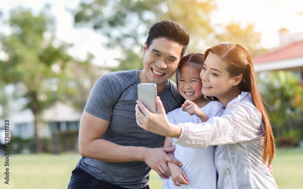 Happy Asian family taking selfie with smartphone together.