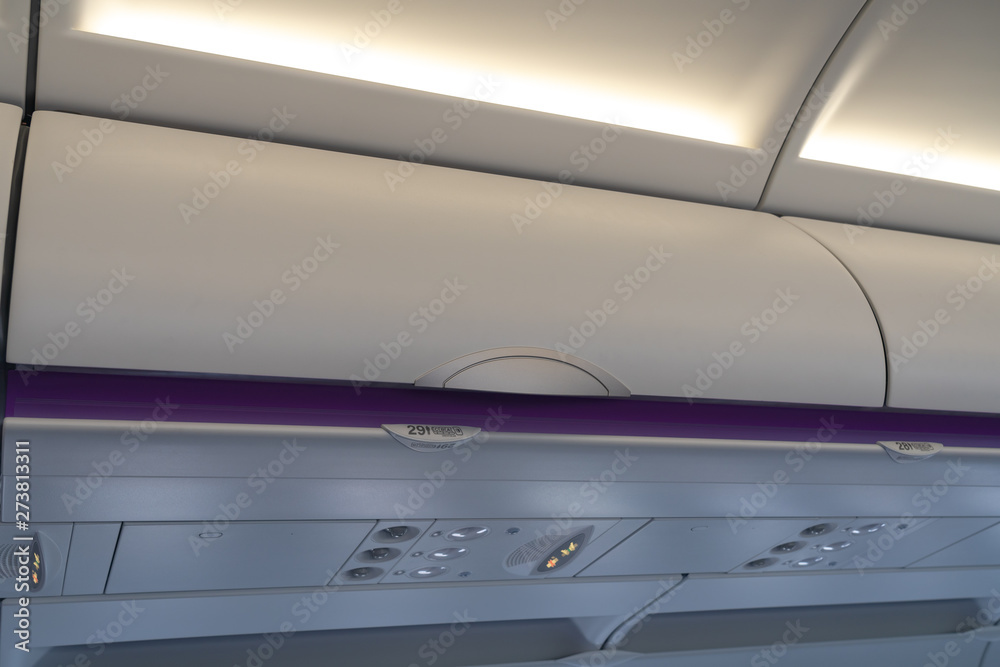Carry-on luggage in overhead storage compartment on commercial airplane. detail shot of an airplane cabin interior. Travel concept with copy space Carry-on luggage in overhead storage compartment on commercial airplane. detail shot of an airplane cabin interior. Travel concept with copy space