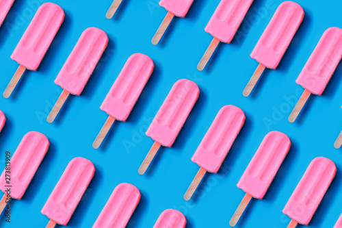 Pattern made of bright pink strawberry ice cream on blue pastel background.