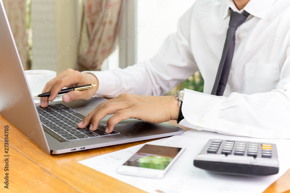Businessman working on laptop with paperwork on table. Businessman working on laptop with paperwork on table.