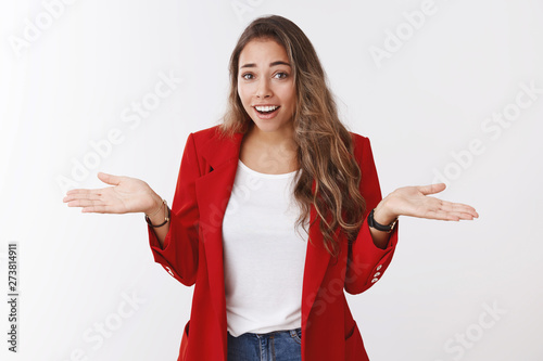 So what. Portrait of arrogant unbothered good-looking modern young stylish woman red jacket, shrugging careless hands sideways smiling gasping indifferent, telling something obvious photo