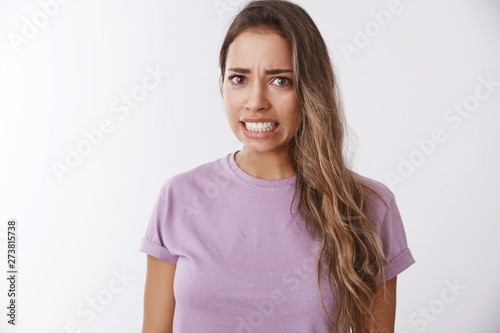 Girl awkward hearing disturbing displeasing story details clenching teeth frowning grimacing aversion, reluctance, showing dislike shock, standing bothered wanna escape uncomfortable situation