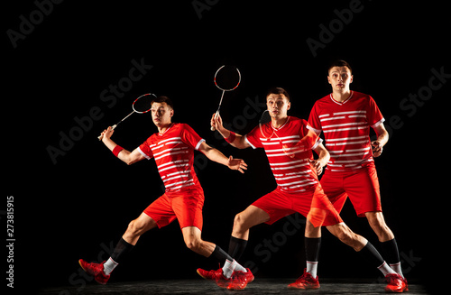 Young man playing badminton isolated on black background in mixed light. Male model in sportwear and sneakers with the racket in action, motion in game. Concept of sport, movement, healthy lifestyle.