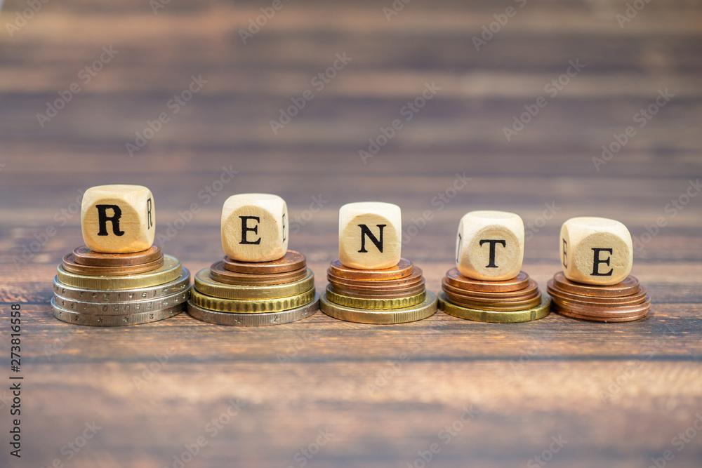 Wood cubes stacked on coins and with the german word for pension, wood background and copy space Wood cubes stacked on coins and with the german word for pension, wood background and copy space