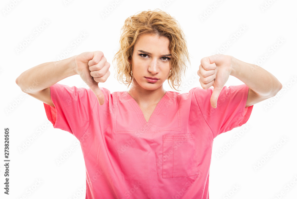 Portrait of young nurse wearing pink scrub showing double dislike gesture Portrait of young nurse wearing pink scrub showing double dislike gesture
