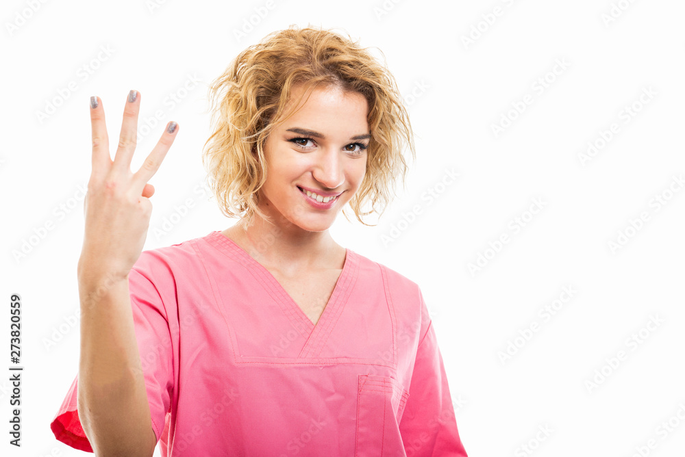 Portrait of nurse wearing pink scrub showing number three Portrait of nurse wearing pink scrub showing number three