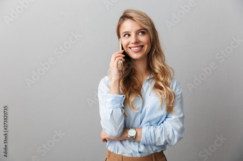 Photo of caucasian blond businesswoman with long curly hair smiling and calling on smartphone photo