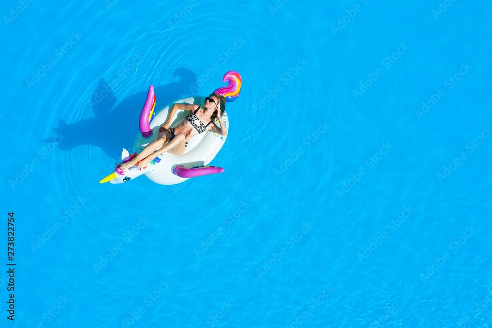 Top view of the pool with a girl in a swimsuit on an inflatable circle. Relaxing and tanning in the summer.