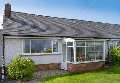 UK 60's bungalow with slate roof, white quartz render and upvc double glazed windows and front porch.