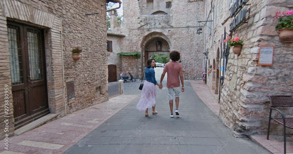 Romantic couple walking visiting rural town of Assisi.Back follow.Friends italian trip in Umbria.4k slow motion