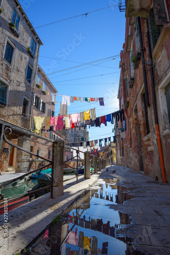 Venice Italy street with laundry washed clothes hanging out to dry on ropes between houses