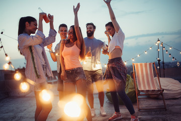 Happy friends with drinks toasting at rooftop party at night