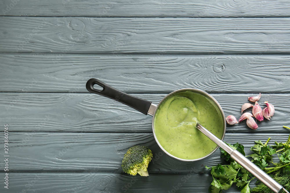 Saucepan with delicious broccoli cream soup on wooden table Saucepan with delicious broccoli cream soup on wooden table