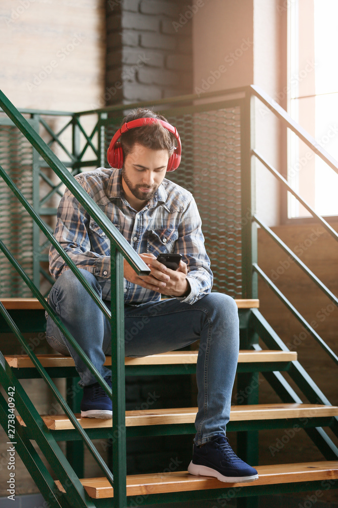 Fototapeta premium Young man listening to audiobook indoors