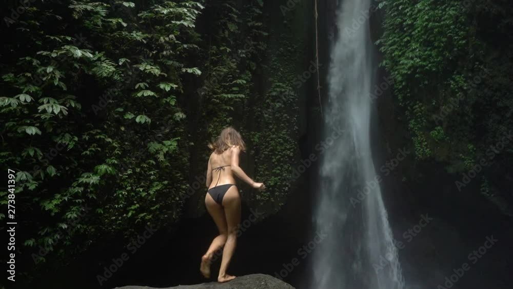 Young pretty woman enjoying near hidden in jungle cascade waterfall in Bali. Young pretty woman enjoying near hidden in jungle cascade waterfall in Bali.