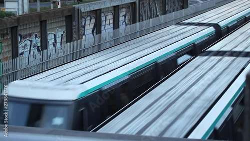Paris, France - April 6, 2019: Two Parisian Metro subway train crossing at medium speed. Motion blur, people, graffiti wall, company logo, transportation, transportation, day.