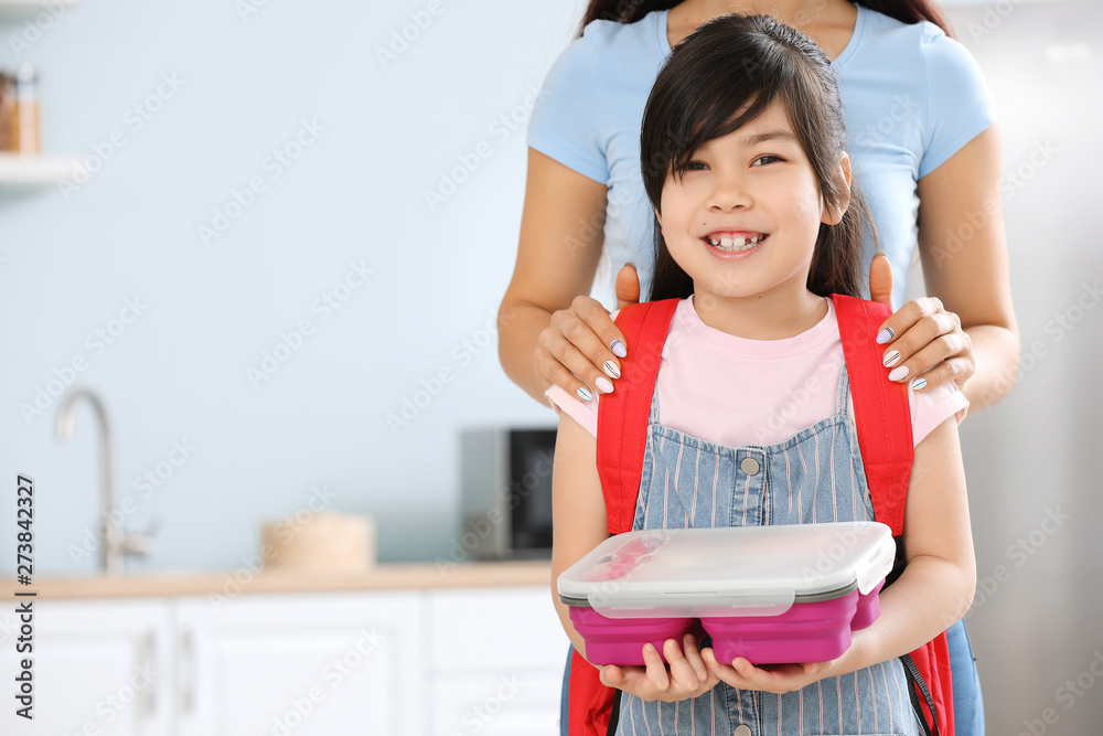 Schoolgirl with mother and lunch box in morning at home Schoolgirl with mother and lunch box in morning at home