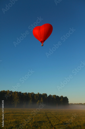 beautiful summer sunny nature landscape with a flying heart-shaped balloon in the blue sky