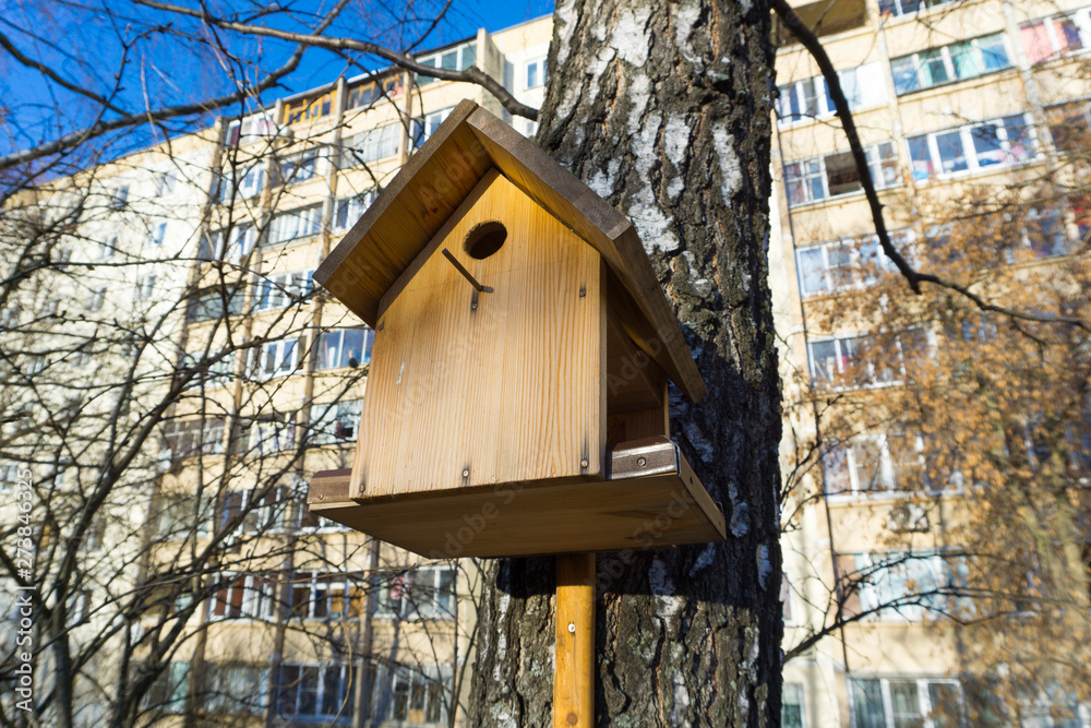 Birdhouse on a birch in winter against the background of a residential building. Birdhouse on a birch in winter against the background of a residential building.