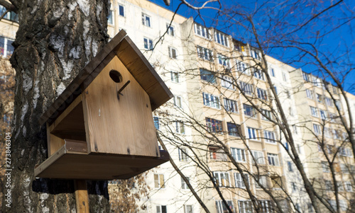 Birdhouse on a birch in winter against the background of a residential building. © Орлов Александр
