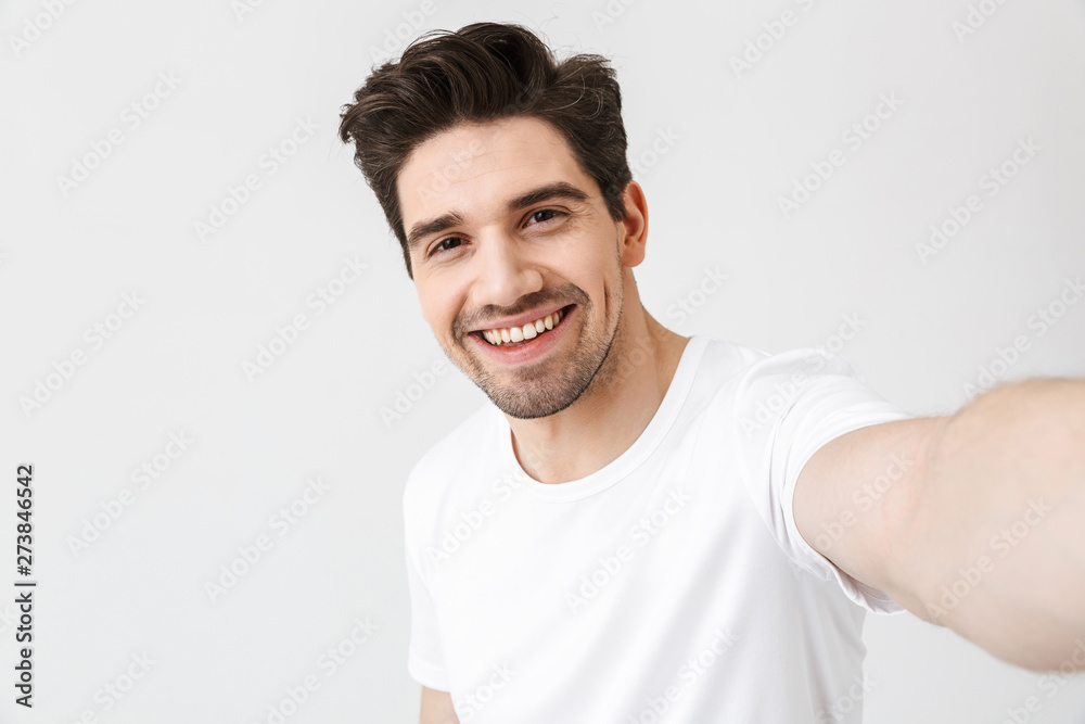 Excited happy young man posing isolated over white wall background make a selfie by camera. Excited happy young man posing isolated over white wall background make a selfie by camera.
