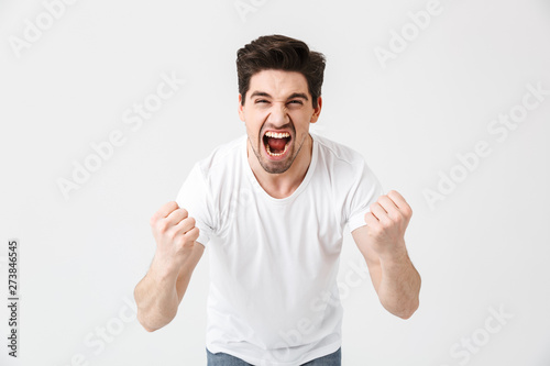 Excited happy young man posing isolated over white wall background.