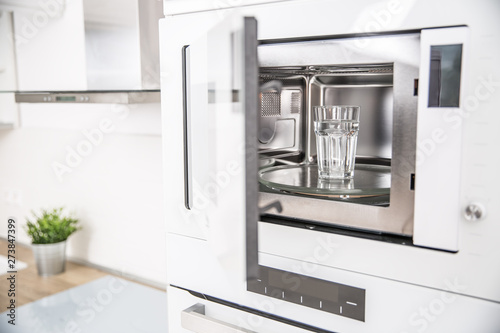 Built-in microwave oven  in the kitchen with a cup of pure water